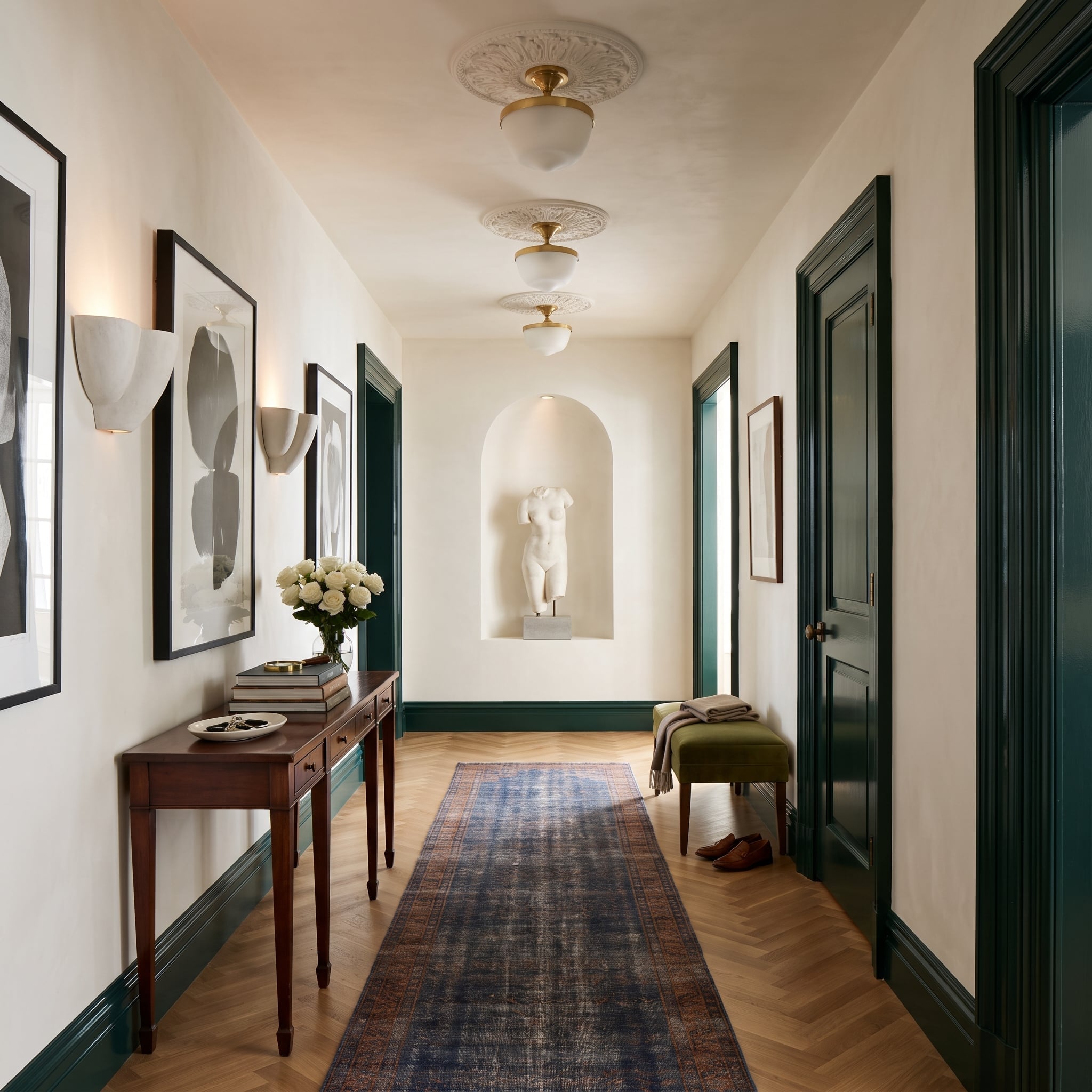Hallway with hunter-green door casings and baseboards, cream walls, herringbone oak floor, and classical sculpture niche