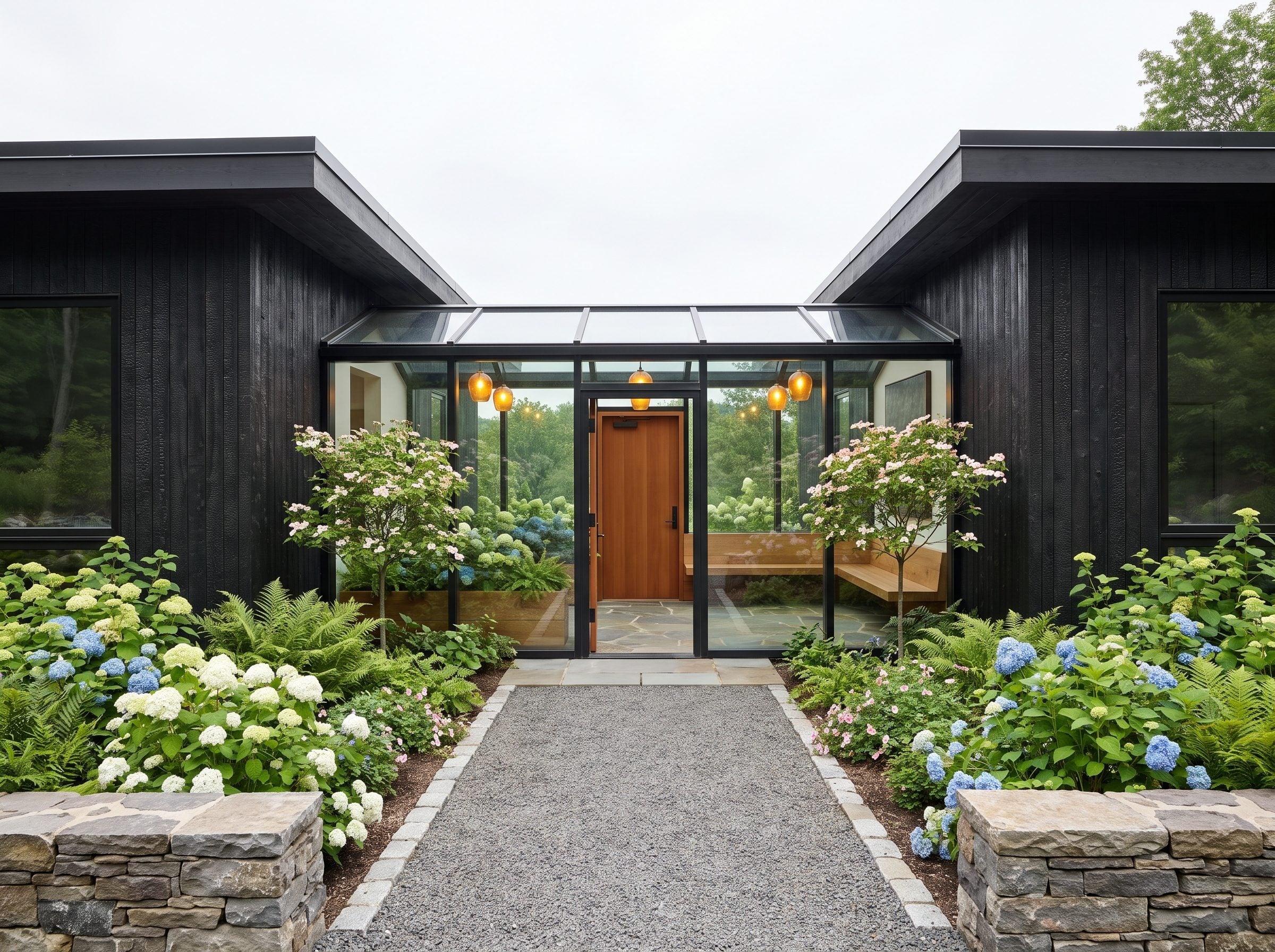 Dark-clad house with a glass-roofed entry pavilion and hydrangea gardens