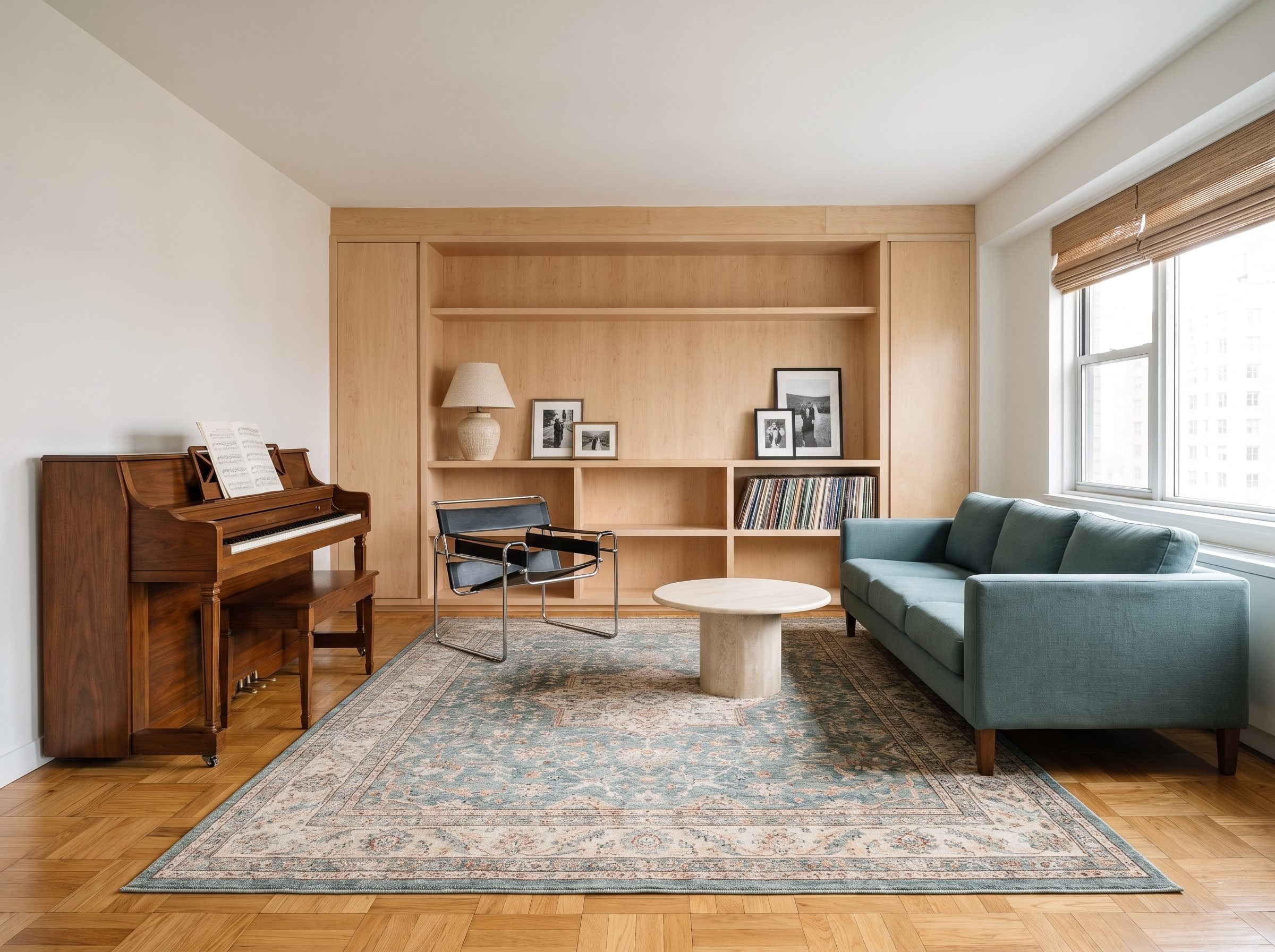 Living room with a dark walnut upright piano, pale maple built-in shelving, blue sofa, and record collection